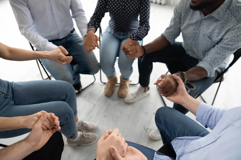 People seated in a circle holding hands.